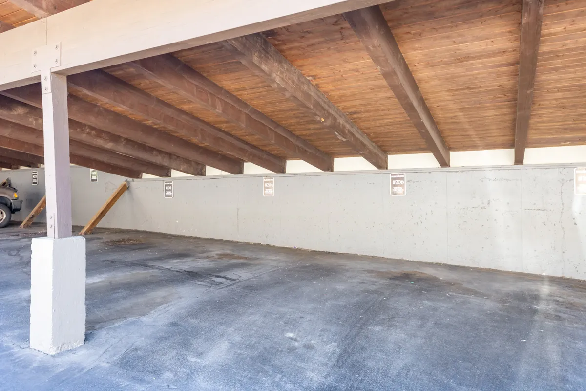 This image shows an interior parking area with clearly visible wooden beams, a concrete wall, and parking spots, reflecting a clean, organized, and practical environment ideal for secure vehicle storage.
