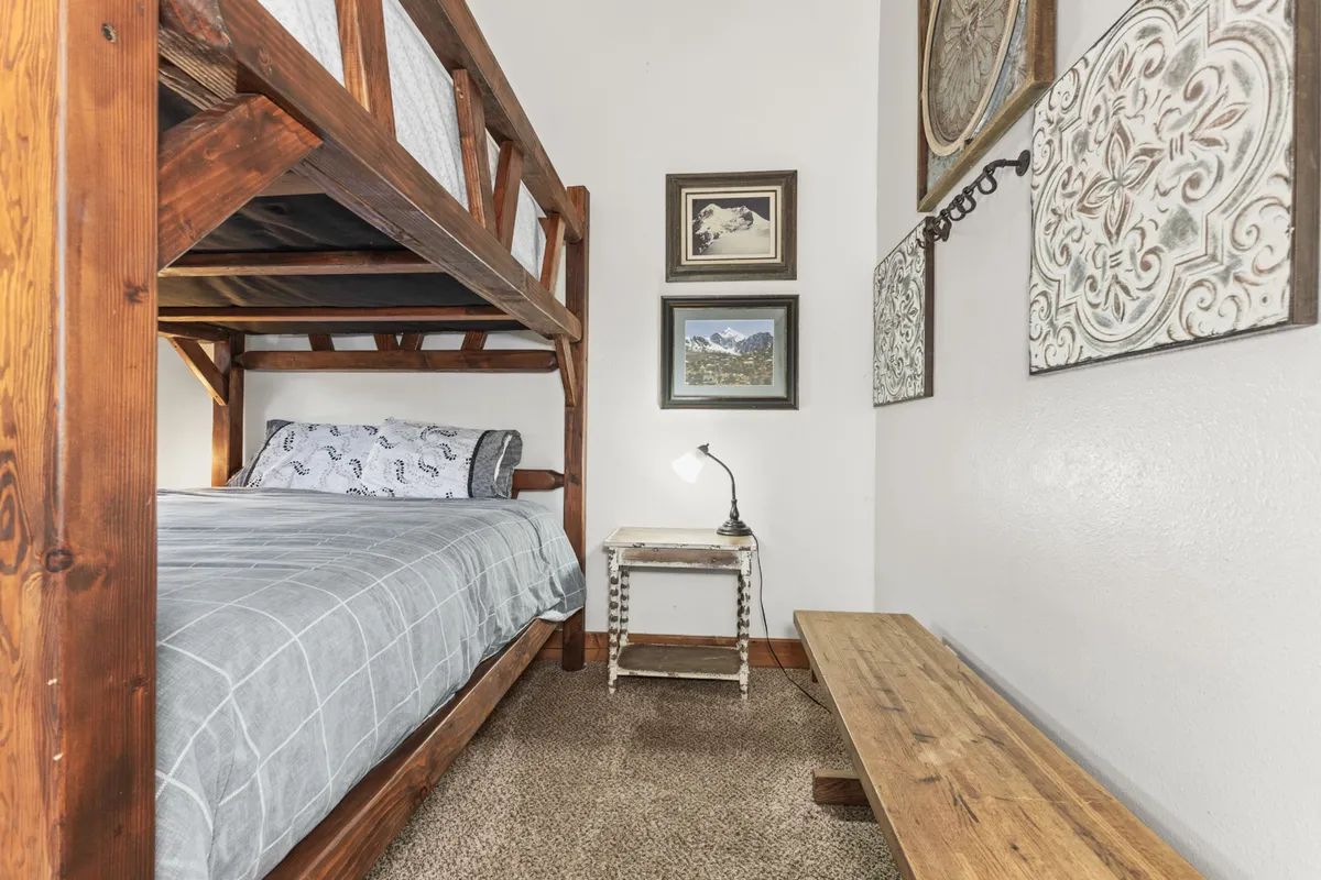 The image shows a comfortable bunk bed with decorative wall art, a table lamp, and a wooden bench, creating an inviting nook for relaxation. The arrangement demonstrates the flexible sleeping options ideal for families or groups, as described in the section.
