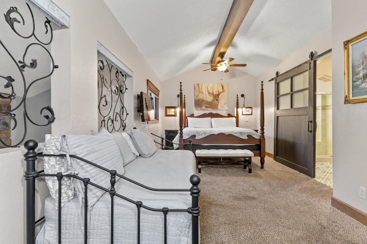 This tranquil master suite features a four-poster bed, a stylish daybed, decorative wall art, and a wooden sliding door. The space feels expansive, welcoming, and ideal for relaxation, reading, or enjoying quiet moments. The presence of multiple beds and elegant decor caters to a variety of group configurations.