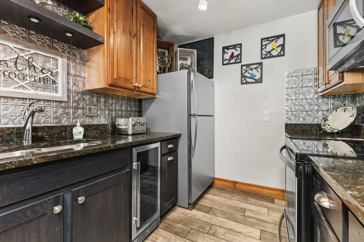 A modern kitchen featuring granite countertops, stainless steel appliances, decorative wall art, and wooden cabinetry, all bathed in warm, welcoming light. Ideal for preparing meals and entertaining guests.
